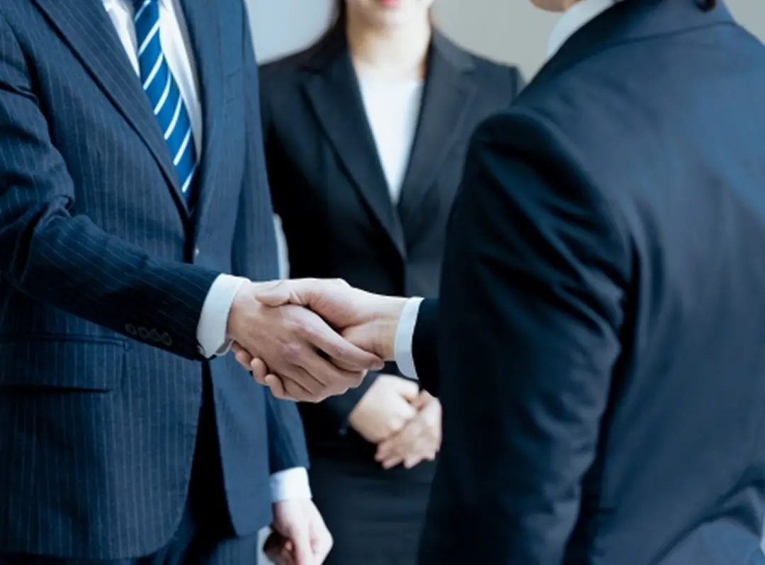 スーツを着た人たちが握手をしている様子
