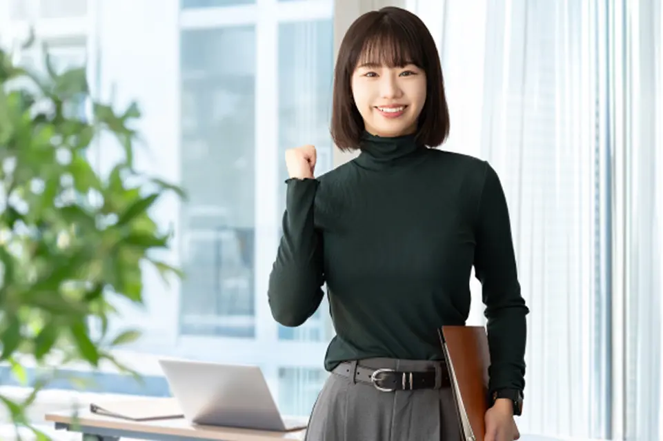 笑顔の女性がガッツポーズをしてこちらを見ている様子